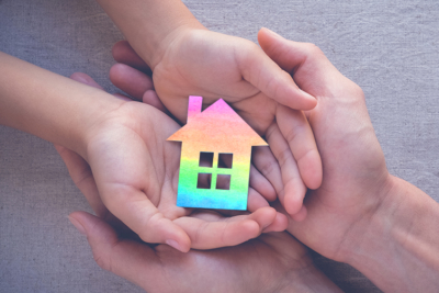 two hands holding a rainbow colored house